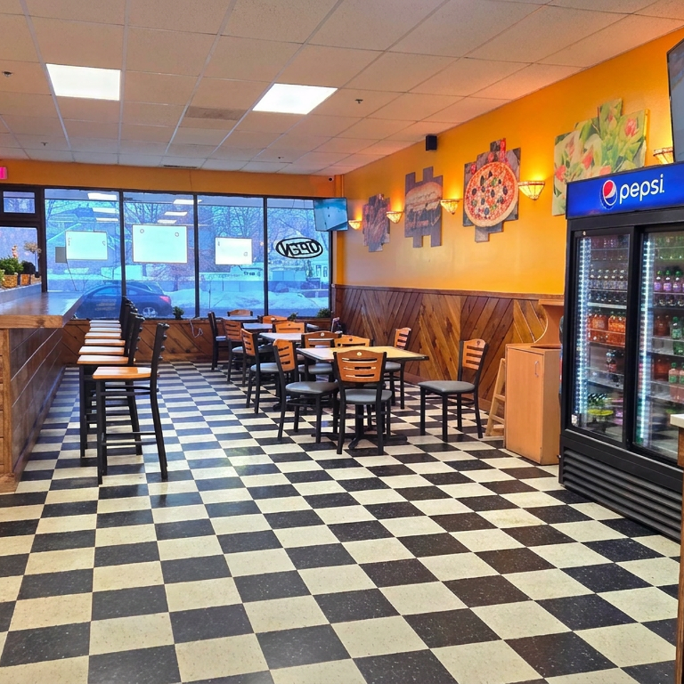 Bright pizzeria dining area with wood-paneled walls, checkered floor, tables, televisions, and Pepsi beverage refrigerators.